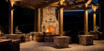 A safe and stylish setup for an outdoor fireplace under a wooden pergola.