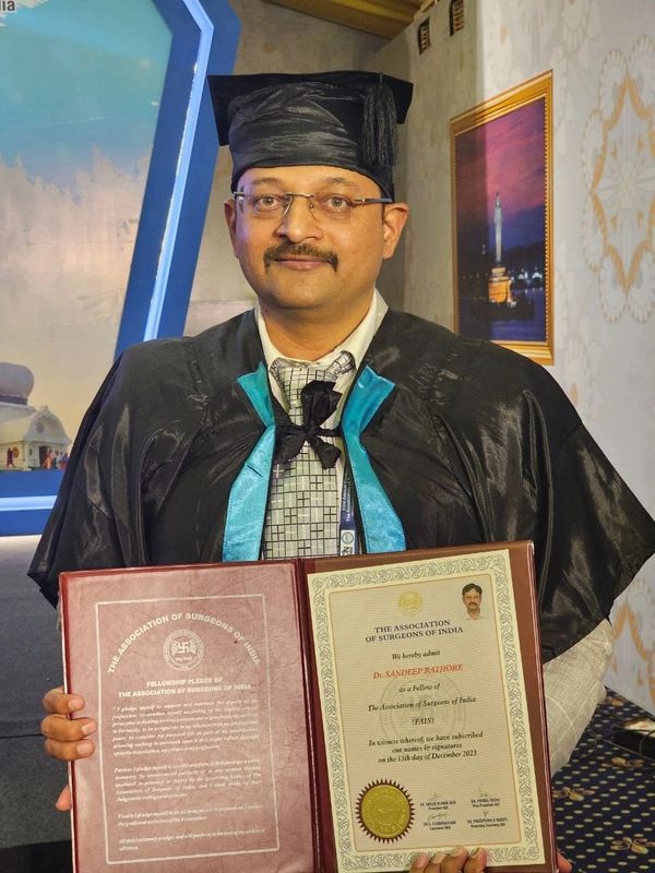 Graduate in academic regalia holding a fellowship certificate from The Association of Surgeons of India.