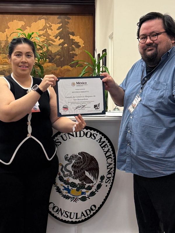Two people holding a certificate at the Mexican consulate office.