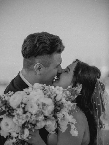 Black and white photo of couple sharing a kiss at wedding.