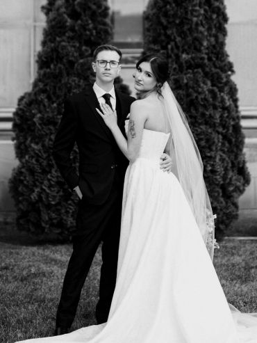 Bride and groom posing outdoors in formal wedding attire.