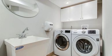 Modern laundry room with washer, dryer, sink, and wall cabinets.