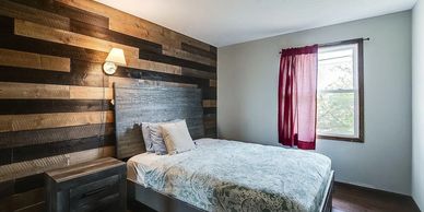 Cozy bedroom with wood accent wall and natural light from window.