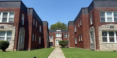 Brick apartment buildings with green lawns and a clear blue sky.
