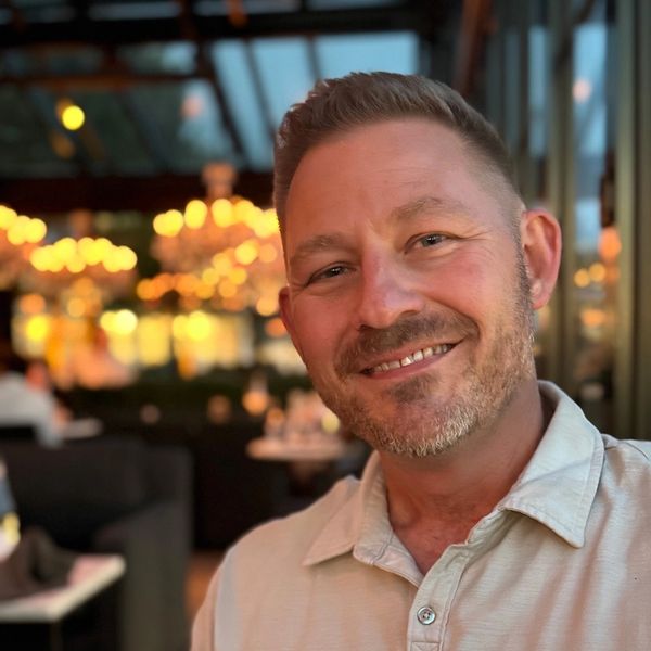 Smiling man in a warmly lit restaurant.