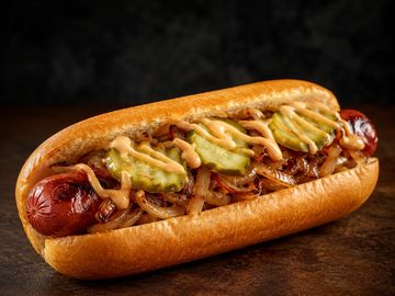 Hot dog with grilled onions and pickles.