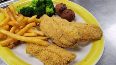 A plate of fried chicken wings , fries and veggies 