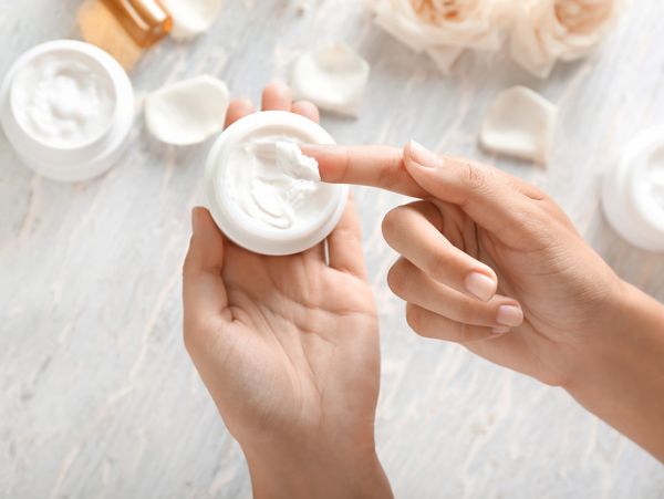 Young woman applying body cream, closeup
