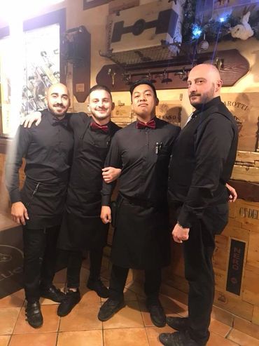 Four male restaurant staff standing together in uniform.