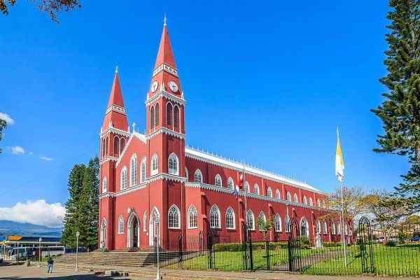 Iglesia roja con dos torres bajo un cielo azul.