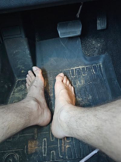 Bare feet on a car floor near pedals.