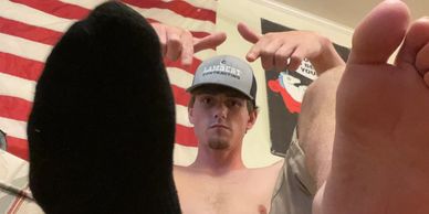 Man pointing towards the camera with feet in foreground.