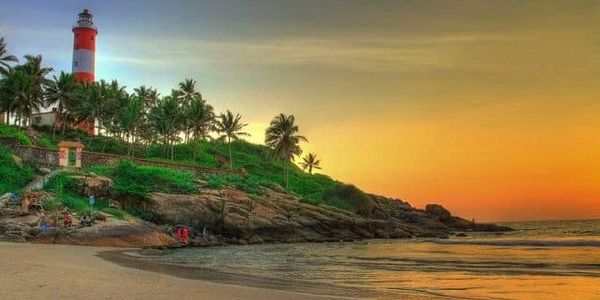 Lighthouse on a cliff at sunset with palm trees.