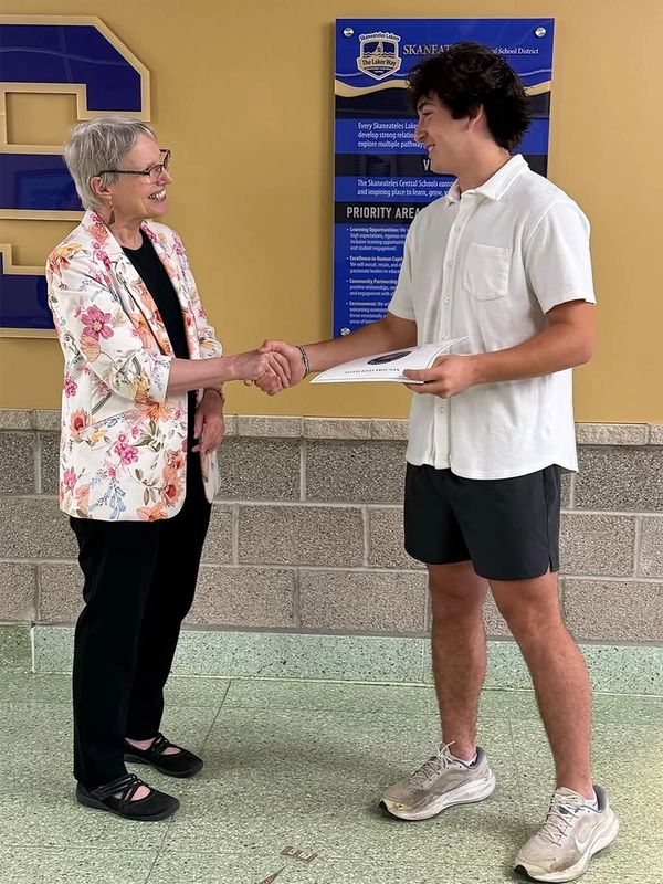 Two people shaking hands, one holding a certificate.
