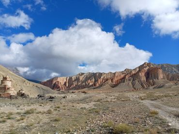 Rock formations under a vibrant blue sky with fluffy clouds.