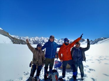 Group of four mountaineers celebrating in snowy mountains.