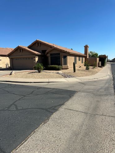 Single-story house on a sunny corner lot with desert landscaping.