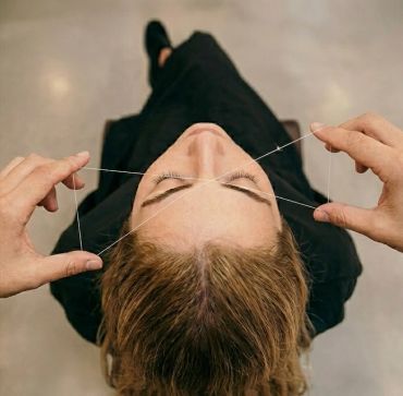 Person getting eyebrows threaded for grooming.
