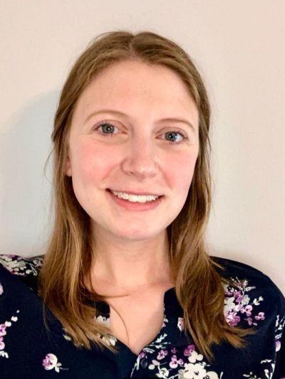 Smiling woman with light brown hair in floral blouse.
