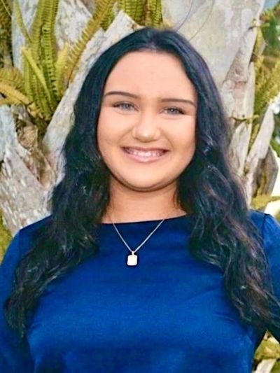 Young woman smiling in front of a tree.