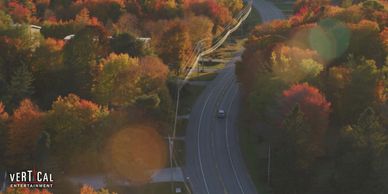 Aerial view of a winding road through autumn-colored trees.