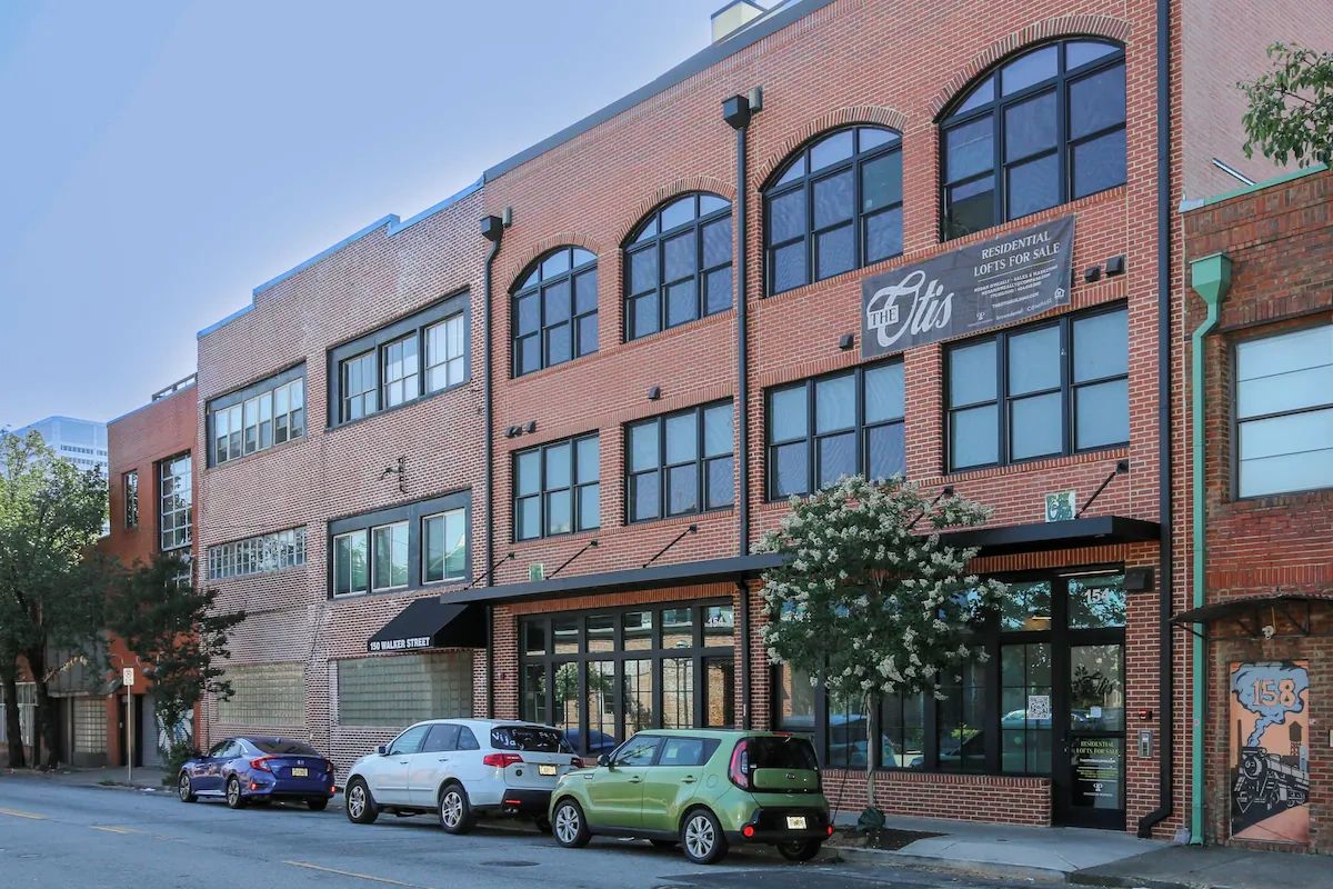Street view of a brick residential loft building with parked cars.