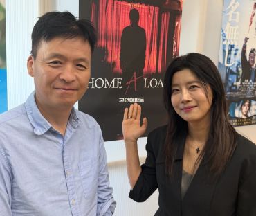 Two people smiling in front of a movie poster.