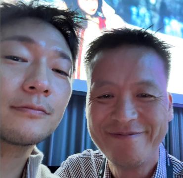 Two men taking a close-up selfie indoors.