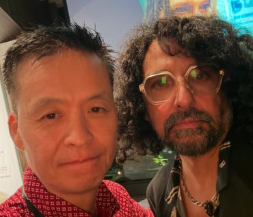 Two men taking a close-up selfie indoors.