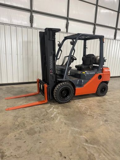 Orange and black Toyota forklift parked inside a warehouse.