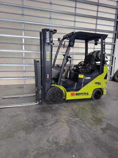 A green Clark forklift parked indoors on a concrete floor.