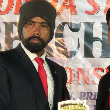 Man in suit and red tie holding a trophy at an event.