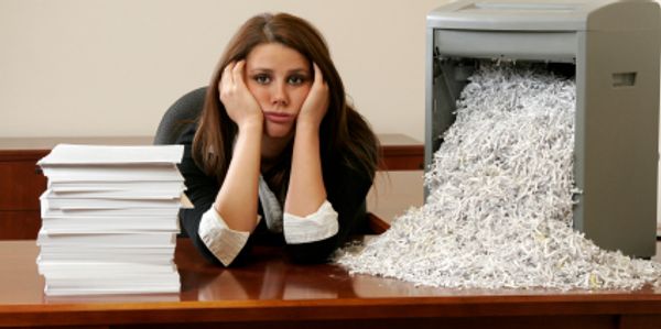 A lady in an office is bored of shredding their own paper