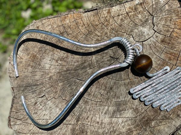 A silver tuning fork with a wooden bead on a tree stump.