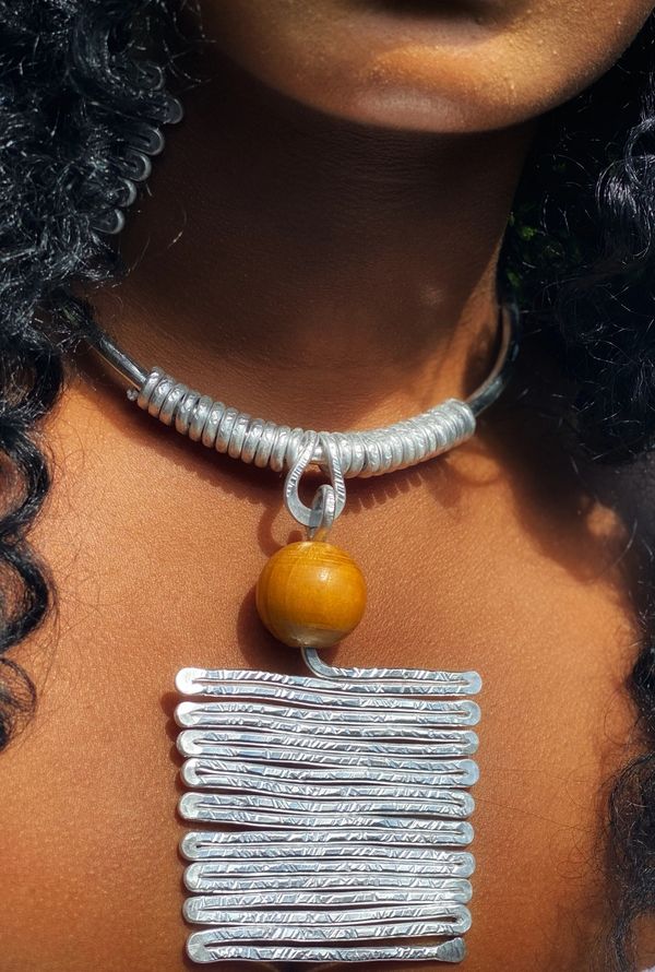 Close-up of a silver necklace with a wooden bead pendant on a woman’s neck.