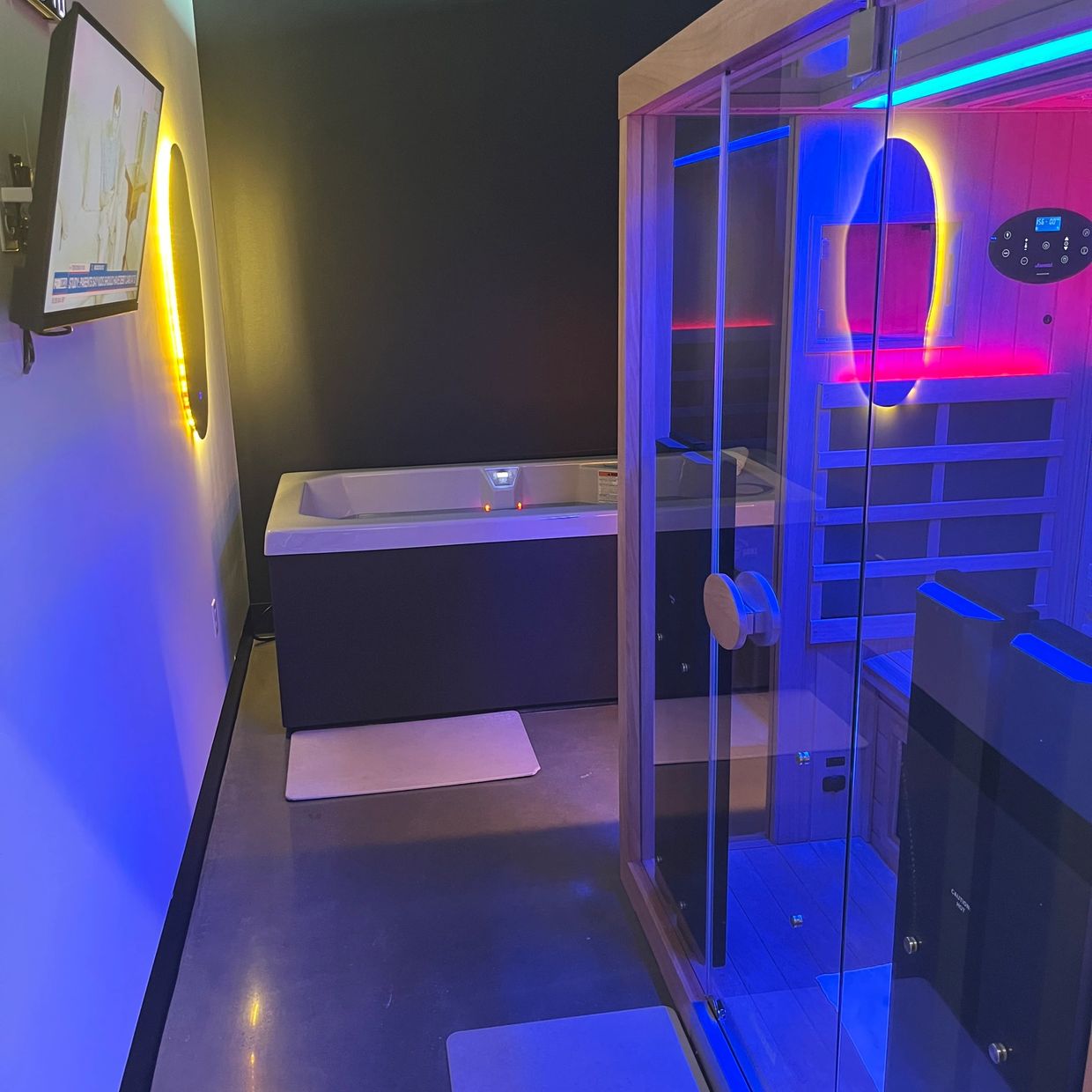 Modern bathroom with illuminated sauna and bathtub.