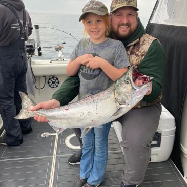 Child and adult holding a large fish on a boat.