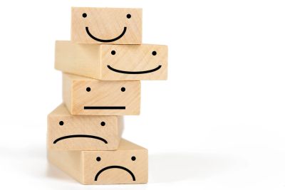 Stacked wooden blocks displaying facial expressions that range from happy to sad.
