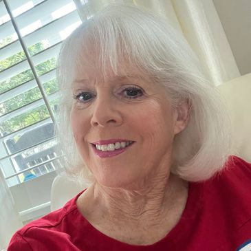 Elderly woman with white hair smiling indoors.