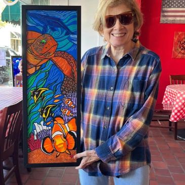Woman holding colorful marine-themed artwork.