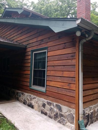 Wooden cabin exterior with stone foundation and chimney.