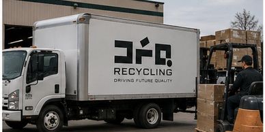 A recycling truck with a forklift loading boxes beside it.