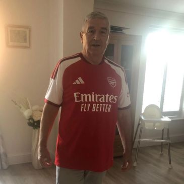Man wearing an Arsenal football jersey indoors.