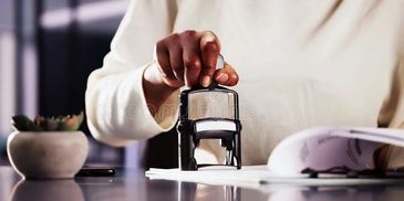 Person using a stamp on paper at a desk.