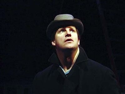Man wearing a hat looking upwards in a dark setting.