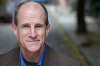 Smiling middle-aged man with a bald head outdoors.