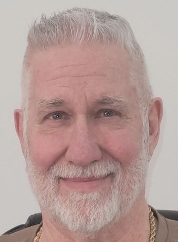 Smiling elderly man with white hair and beard.