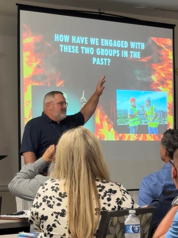 Man giving presentation in front of a screen with question about engagement.