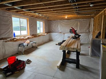 Unfinished basement with construction tools and wooden planks.