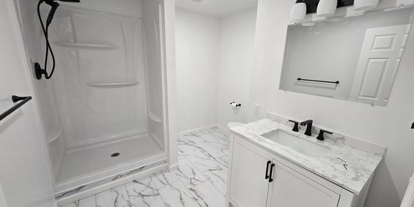 Modern white bathroom with marble flooring and black fixtures.
